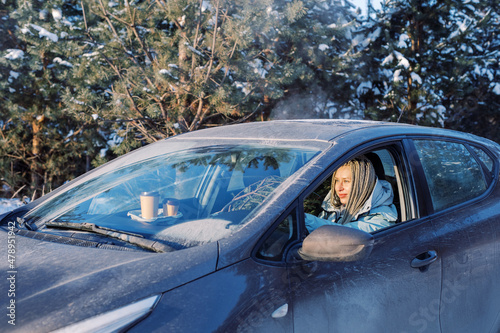 Woman driving through forest with a fir tree photo