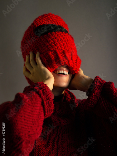 Young woman laughs and puts on a knitted balaclava