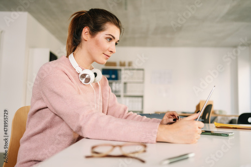 Young woman working on a laptop with headphones around her neck Fototapete