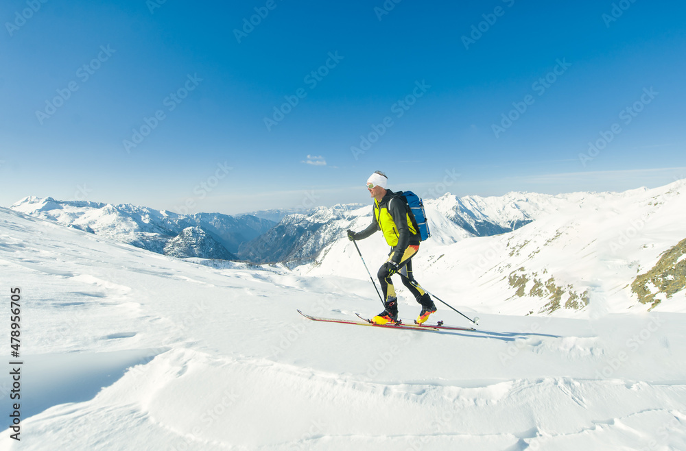 A ski mountaineer climbs with sealskins under his skis