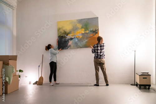 Happy diverse couple carrying colorful painting