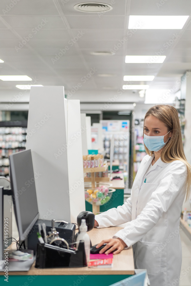 Pharmacist working at computer in pharmacy