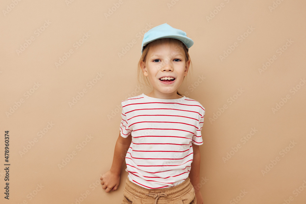 Portrait of happy smiling child girl in blue caps striped t-shirt emotions beige background Portrait of happy smiling child girl in blue caps striped t-shirt emotions beige background