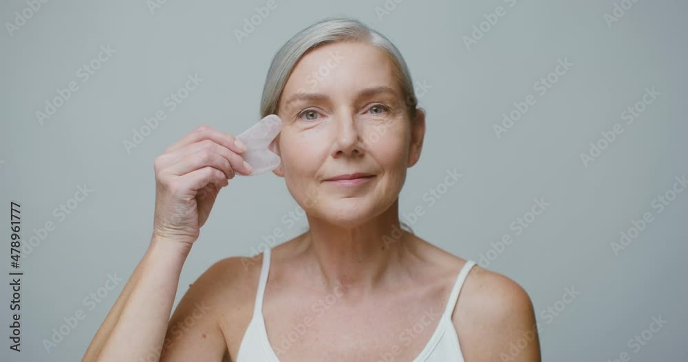An elderly model doing a facial massage using a Gua Sha stone An elderly model doing a facial massage using a Gua Sha stone
