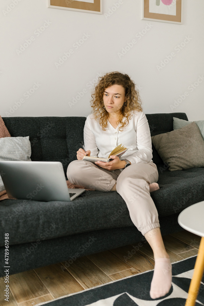 Young female looking at the computer and taking notes Young female looking at the computer and taking notes