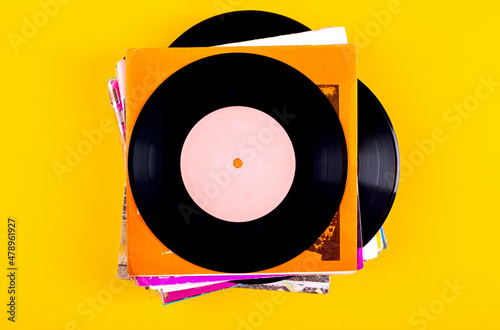 A stack of old vinyl records on a yellow background.Top view.
