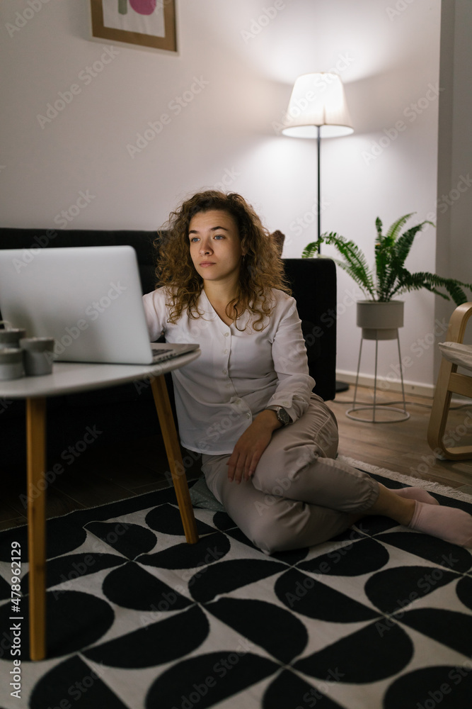 Woman working from home using laptop in evening Woman working from home using laptop in evening