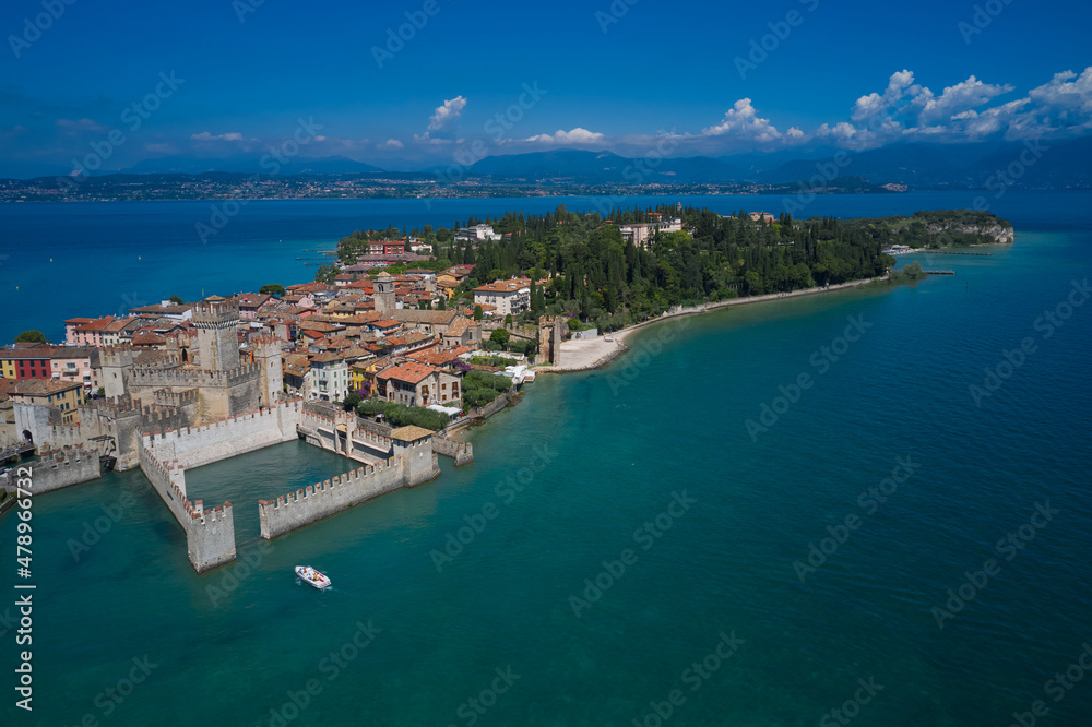 Aerial view on Sirmione sul Garda. Italy, Lombardy. Rocca Scaligera Castle in Sirmione. View by Drone. Boat with tourists near the main castle.