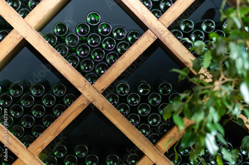 Fotografia Resting wine bottles stacked on wooden racks in cellar