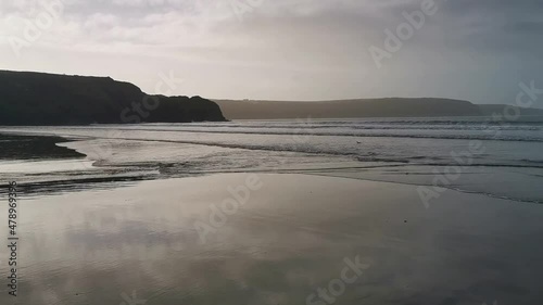 The tide coming in across a sand and pebble beach in Broad Haven, West Wales in early evening photo