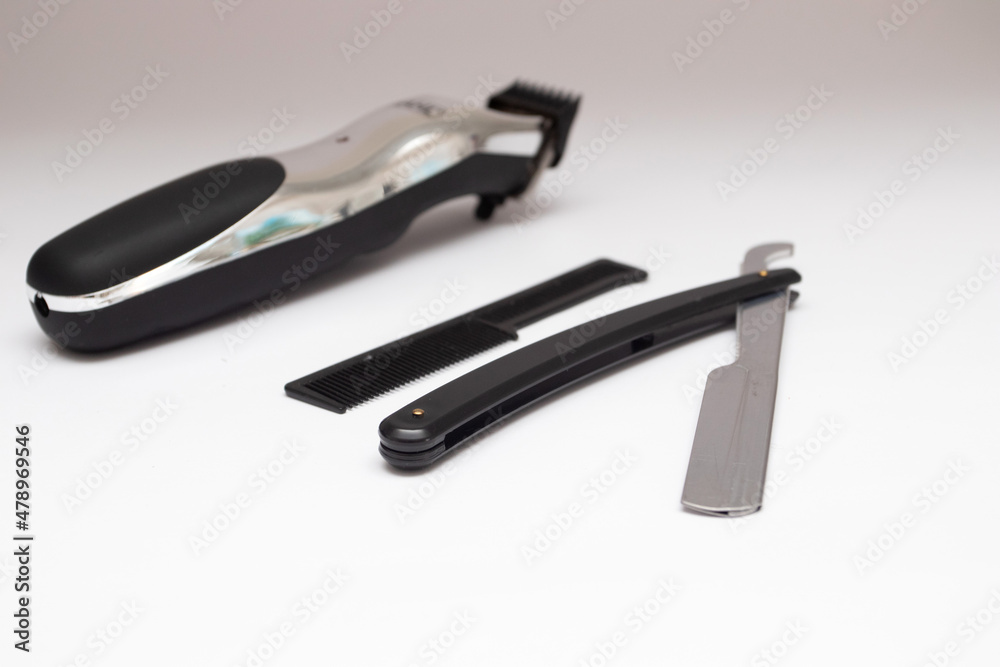 Black straight razor and electric trimmer on a white background Black straight razor and electric trimmer on a white background