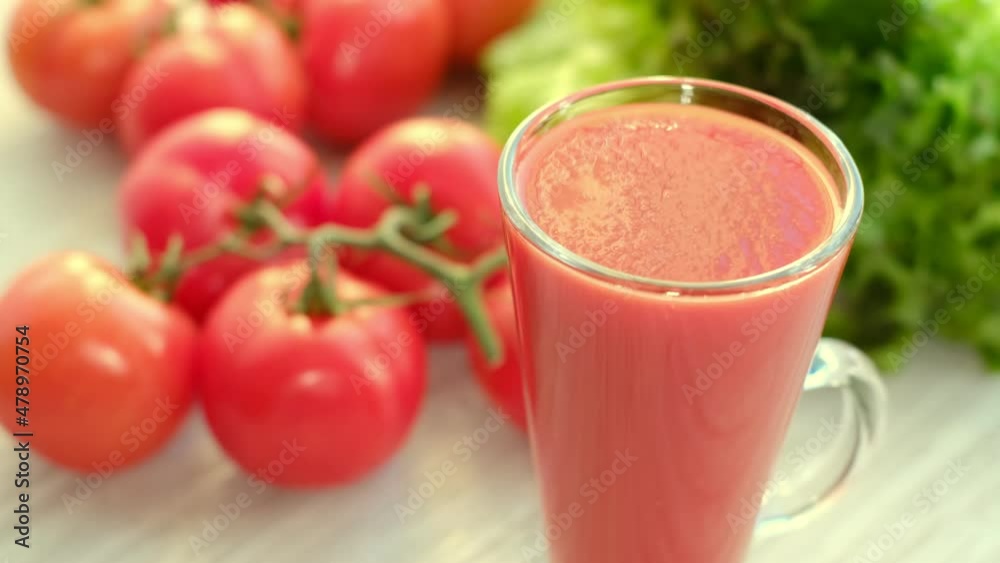 tomato juice with sprig of tomatoes on background. Tomato juice is poured into a glass.