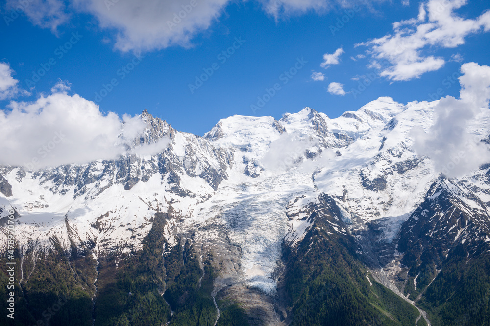 The Mont Blanc Massif and white clouds in the Mont Blanc Massif in Europe, France, the Alps, towards Chamonix, in summer on a sunny day.