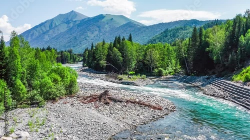 Aerial footage of river and green forest with mountain natural landscape in Xinjiang, China. Green nature landscape in summer season.