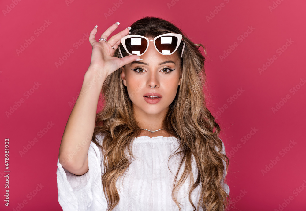 Charming female with sunglasses looking at camera on pink background Charming female with sunglasses looking at camera on pink background