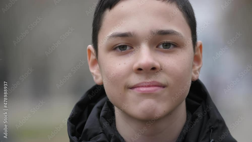 Portrait of a 13-year-old boy, standing on the street in autumn, he looks at the camera and smiles. Close-up, shallow depth of field Portrait of a 13-year-old boy, standing on the street in autumn, he looks at the camera and smiles. Close-up, shallow depth of field