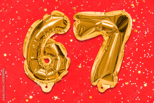 The number of the balloon made of golden foil, the number sixty-seven on a red background with sequins. Birthday greeting card with inscription 67. Numerical digit, Celebration event, template. photo