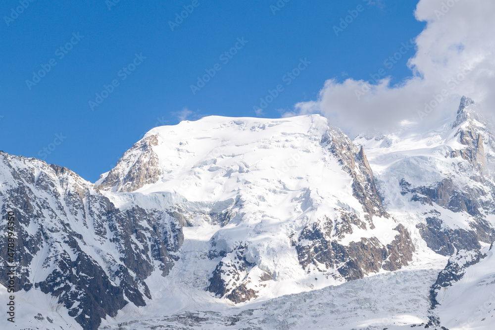 The close-up of Mont Blanc du Tacul surrounded by clouds in the Mont Blanc Massif in Europe, France, the Alps, towards Chamonix, in summer, on a sunny day.