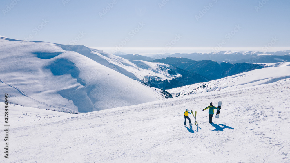 couple skier and snowboarder at the top of the mountains at sunny day