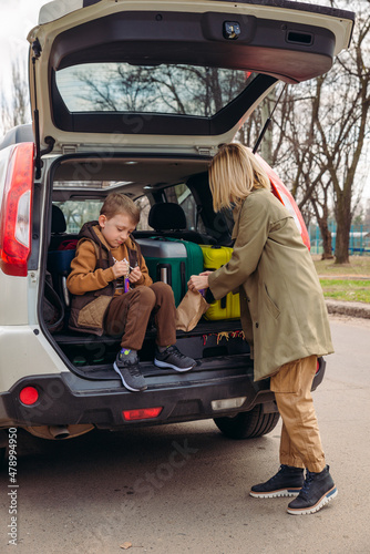 little kid sitting with mother in car trunk full of luggage eating chocolate candies