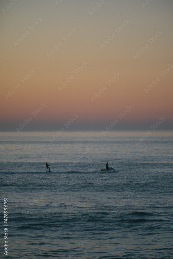 Fototapeta premium Jet ski towing a foil surfer during the sunset on atlantic ocean