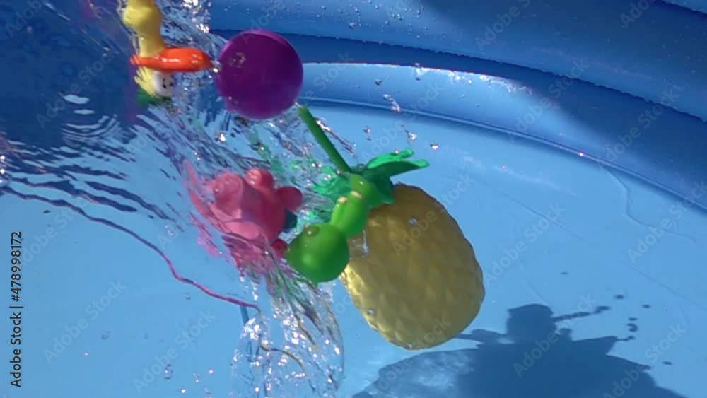Toys and a plastic pineapple falling on a pool.