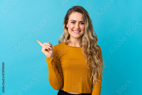 Young Brazilian woman isolated on blue background pointing to the side to present a product