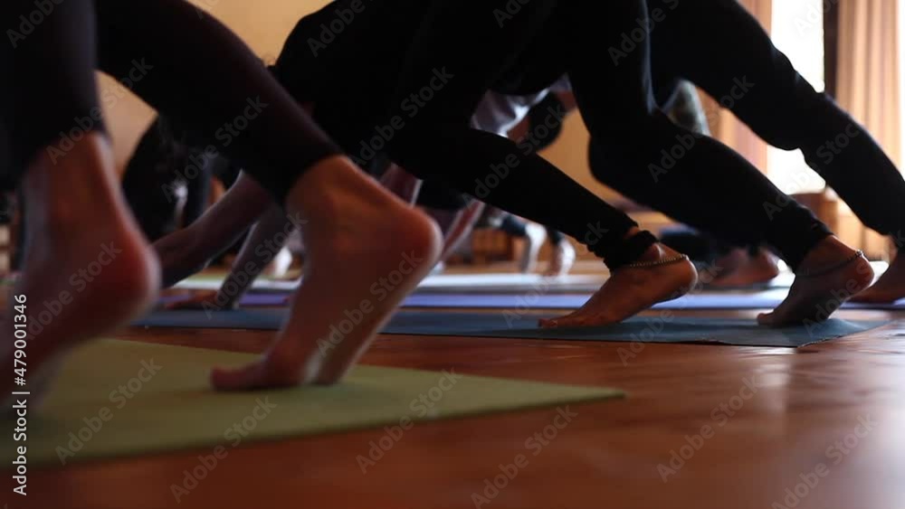 Detail of several people practicing yoga in a circle. They are in downward facing dog Detail of several people practicing yoga in a circle. They are in downward facing dog