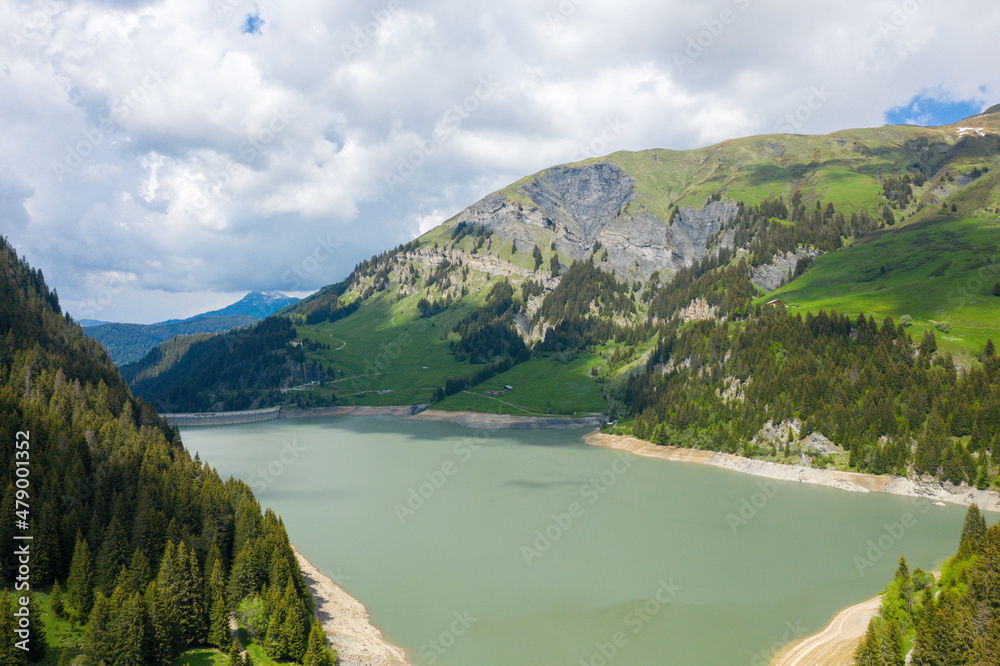 The lake and the Dam of Saint Guerin in Europe, in France, towards Beaufort, in the Alps, in summer, on a sunny day.