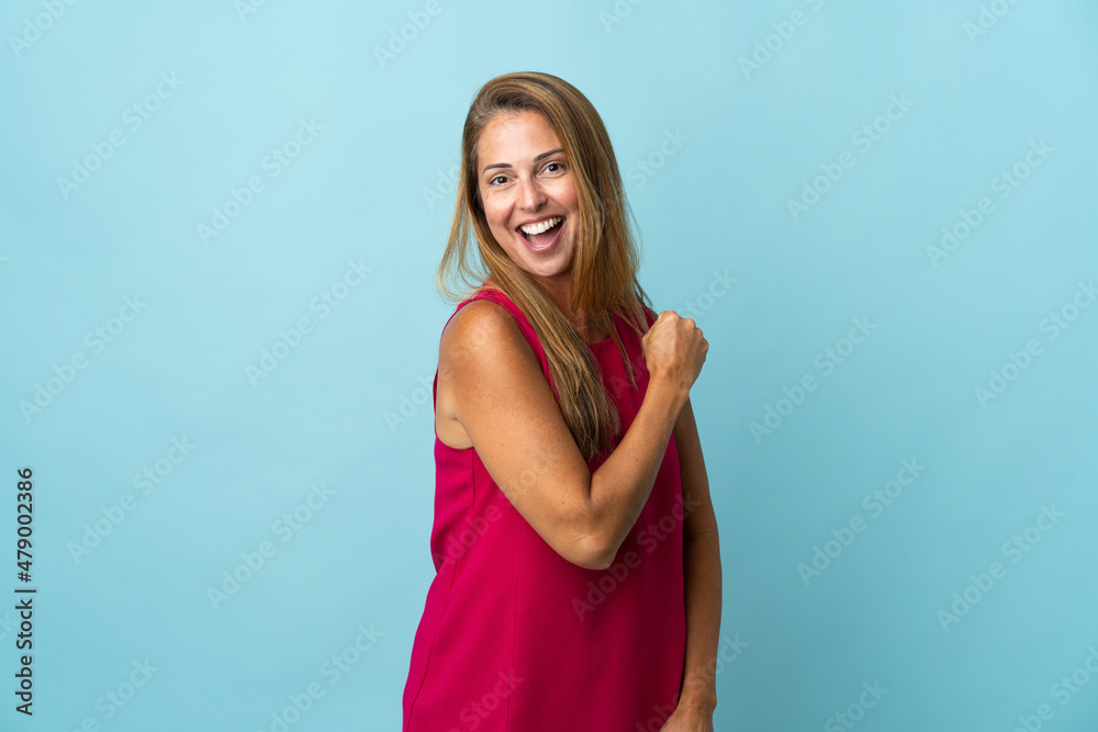 Middle age brazilian woman isolated on blue background celebrating a victory
