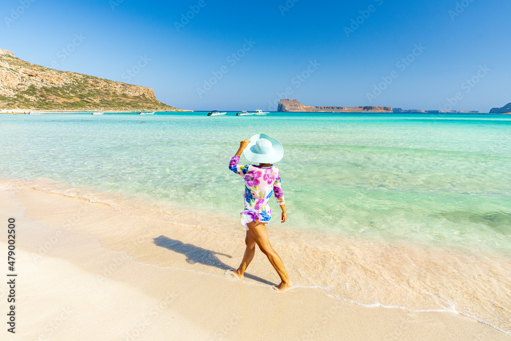 Beautiful woman with sun hat walking on idyllic empty beach, Crete, Greek Islands Beautiful woman with sun hat walking on idyllic empty beach, Crete, Greek Islands