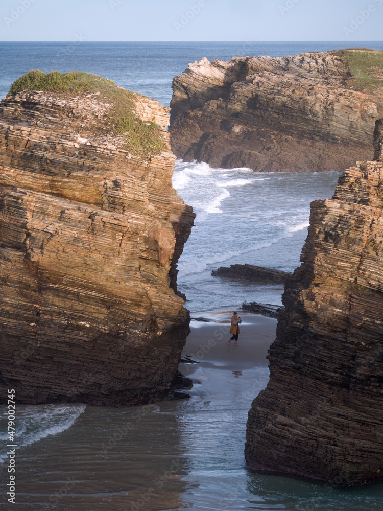 Naklejka premium Las Catedrales beach, Ribadeo, Galicia, Spain. Female tourist making photos surrounded by cliffs.