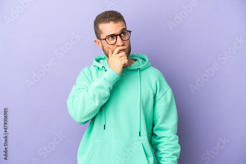 Young handsome caucasian man isolated on purple background having doubts and with confuse face expression © luismolinero