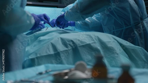 Team of professional medical surgeons performs the surgical operation in a modern hospital. Doctors are working to save the patient. Medicine, health, cardiology and transplantation concept.