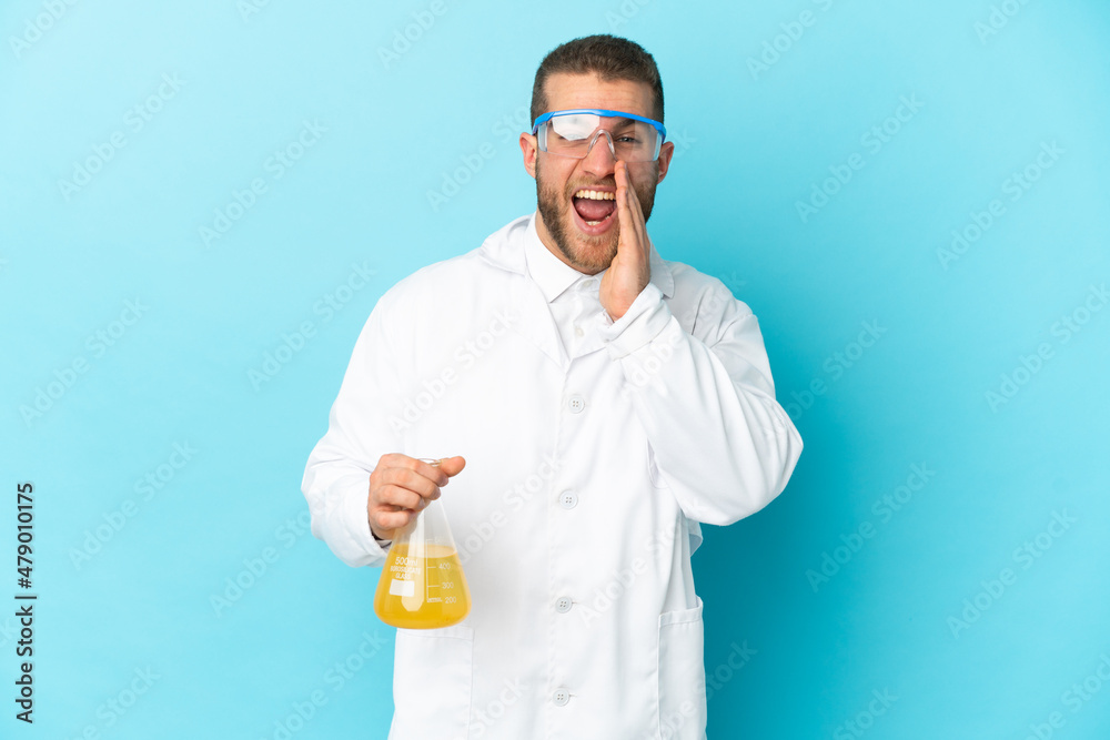 Young caucasian scientific man isolated on blue background shouting with mouth wide open Young caucasian scientific man isolated on blue background shouting with mouth wide open