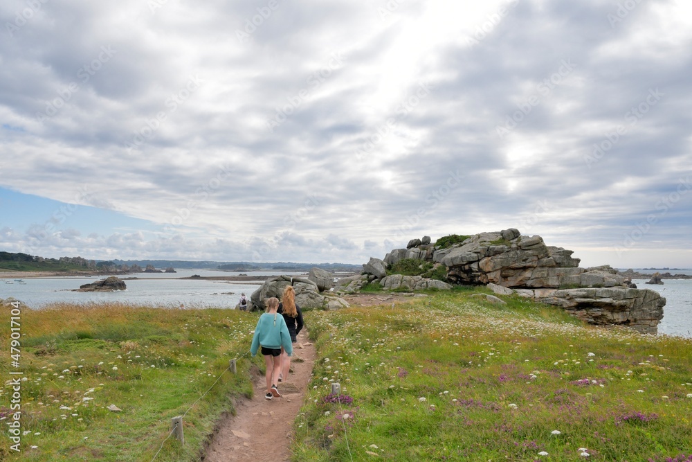 Teenage girls walking on a path along the pink granite coast  in Brittany-France