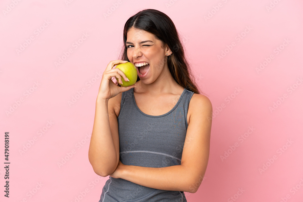 Young caucasian woman isolated on pink background eating an apple Young caucasian woman isolated on pink background eating an apple
