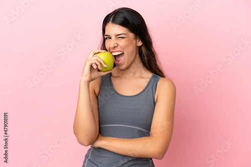 Young caucasian woman isolated on pink background eating an apple