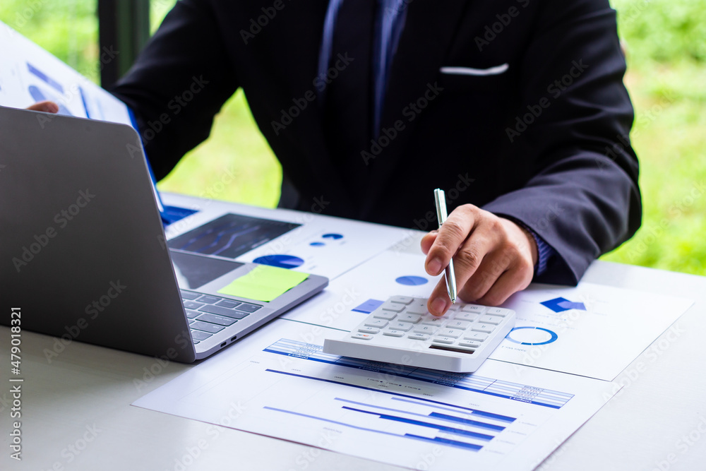 Male finance worker calculates last quarter's earnings figures and points to documents to present, business man checks company income and finance documents, modern business man concept. Male finance worker calculates last quarter's earnings figures and points to documents to present, business man checks company income and finance documents, modern business man concept.