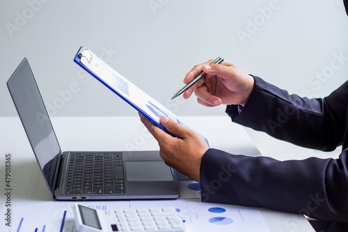 Male accountant calculates last quarter's earnings figures and points to documents to present, business man checking company income and finance documents, modern business man concept.