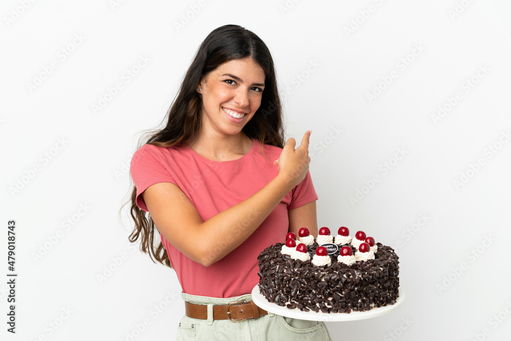 Young caucasian woman holding birthday cake isolated on white background pointing back Young caucasian woman holding birthday cake isolated on white background pointing back