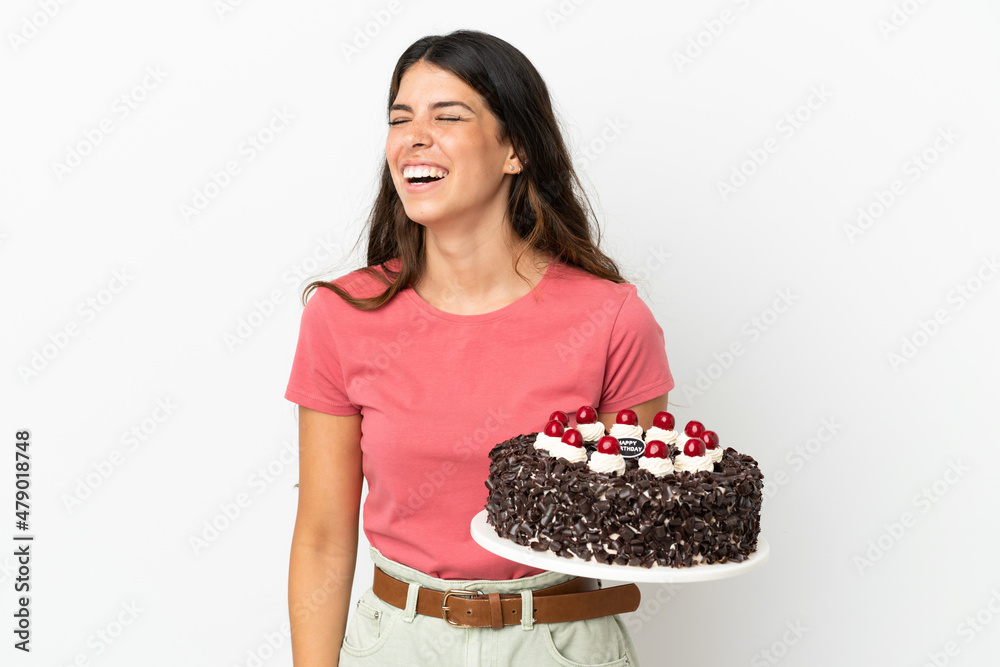 Young caucasian woman holding birthday cake isolated on white background laughing in lateral position Young caucasian woman holding birthday cake isolated on white background laughing in lateral position