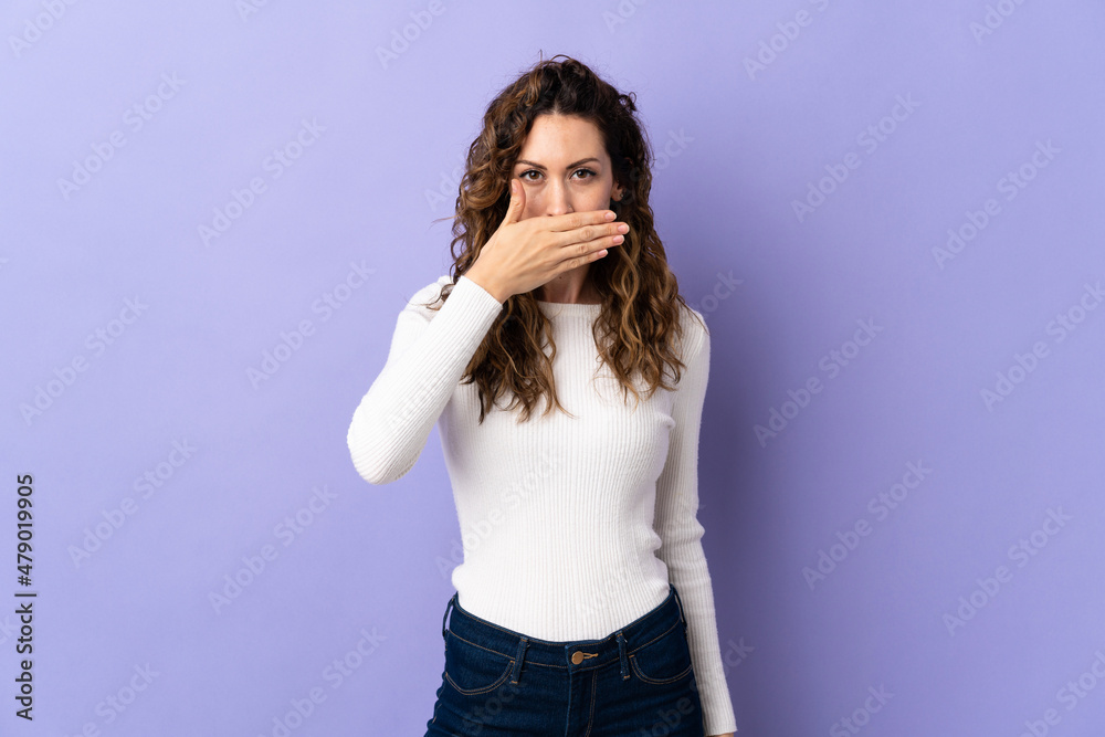Young caucasian woman isolated on purple background covering mouth with hand Young caucasian woman isolated on purple background covering mouth with hand