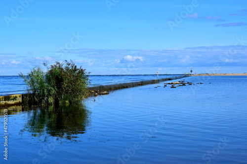 A view of a vast walkway leading right into the sea with water reservoirs on both sides and some small beach visible in the distance spotted on a sunny summer day on a Polish countryside © Rafal