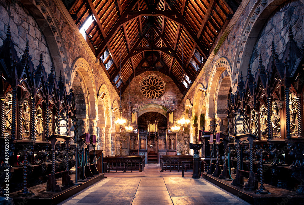 Gothic style church interior with warm internal lighting and wooden roof - stunning brickwork and full wooden furniture and pew seating. 