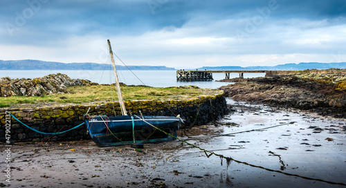 фотографія A small old sailing boat lies aground at Portencross Harbour