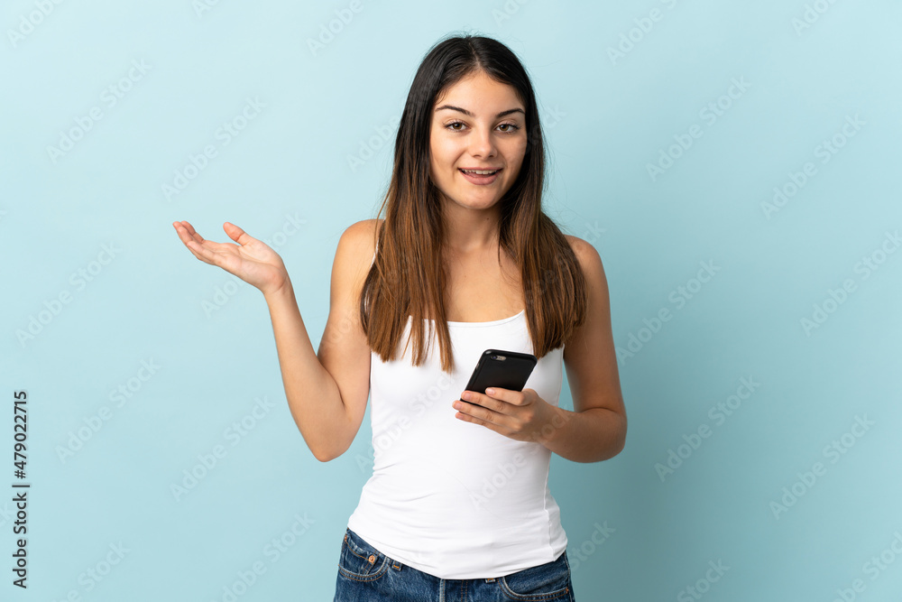 Young caucasian woman using mobile phone isolated on blue background with shocked facial expression Young caucasian woman using mobile phone isolated on blue background with shocked facial expression