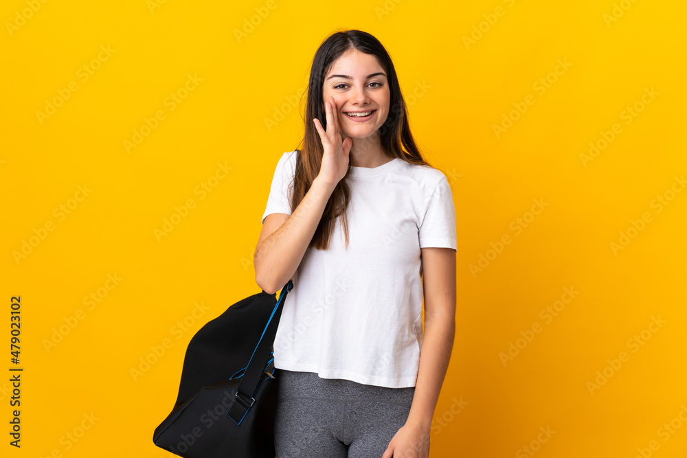 Young sport woman with sport bag isolated on yellow background shouting with mouth wide open Young sport woman with sport bag isolated on yellow background shouting with mouth wide open