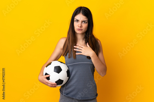 Young football player woman isolated on yellow background surprised and shocked while looking right © luismolinero