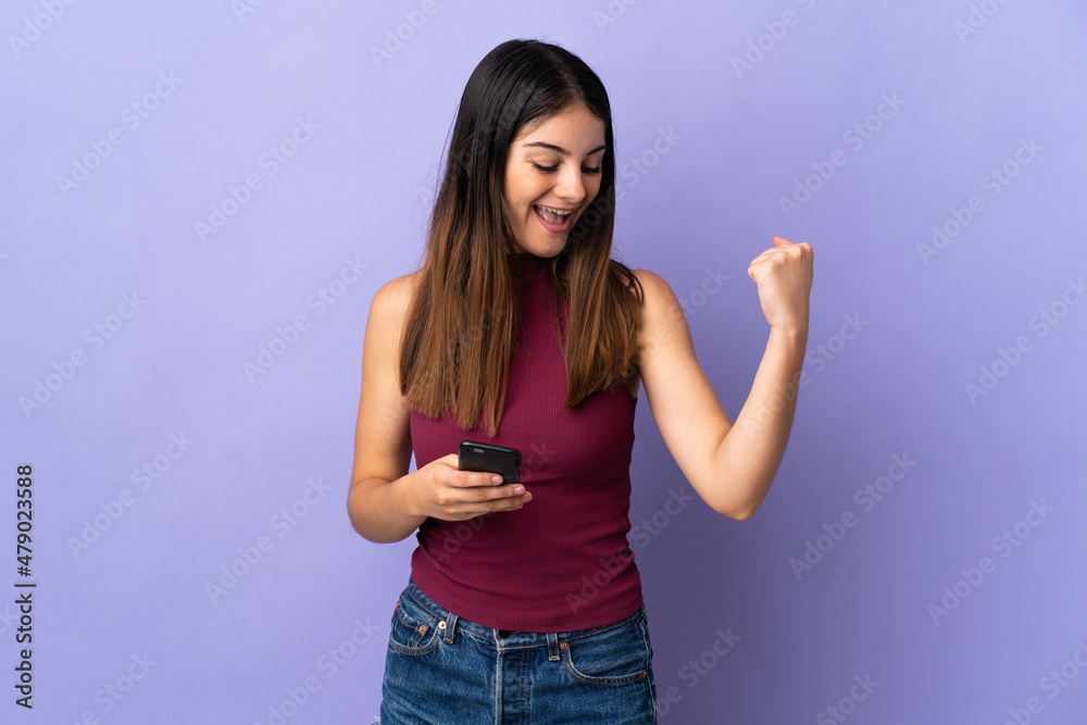 Young caucasian woman isolated on purple background with phone in victory position Young caucasian woman isolated on purple background with phone in victory position